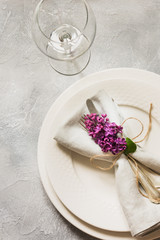 Spring elegant table place setting with violet lilac, silverware on vintage table. View from above.