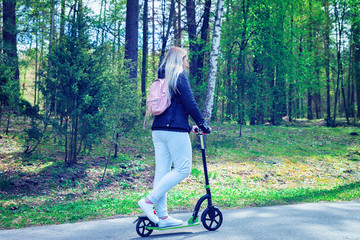 Young woman on push scooter in park in Druskininkai toned