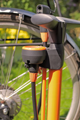 Close-up of an orange bicycle air pump in front of the wheel of a bicycle