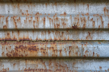 Rusty metal background with old layers of silver paint. Texture rusted shipping container