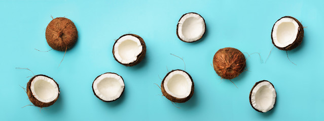 Pattern with ripe coconuts on blue background. Top View. Copy Space. Pop art design, creative summer concept. Banner. Half of coconut in minimal flat lay style.