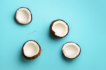Pattern with ripe coconuts on blue background. Top View. Copy Space. Pop art design, creative summer concept. Half of coconut in minimal flat lay style.