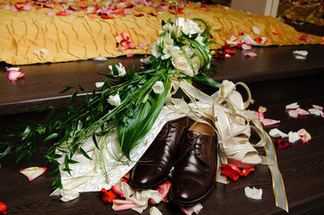Brown male and white female summer wedding shoes on the rose petals. A beautiful bouquet of the bride.