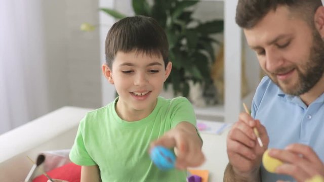 Boy with his father paint traditional Easter eggs