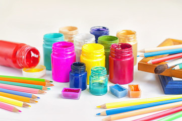 Accessories for drawing on a light background. Acrylic paint, watercolor and colored pencils.