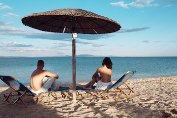 Couple in love with sexy body relax on beach. Summer holidays and paradise travel vacation. Love relations of naked couple at sea. Sexy woman and man suntan at umbrella. Family and valentines day.