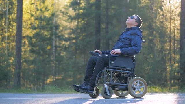 A person in glasses sits in a wheelchair.