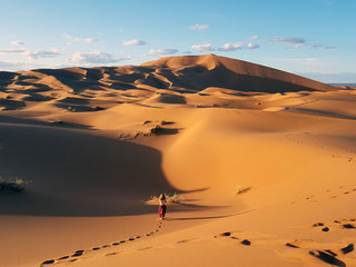 Fototapeta na wymiar Girl walking on the sand of the desert in sunny day