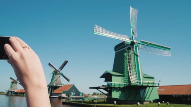 Steadicam shot: woman takes pictures of old windmills in Zaans Schans