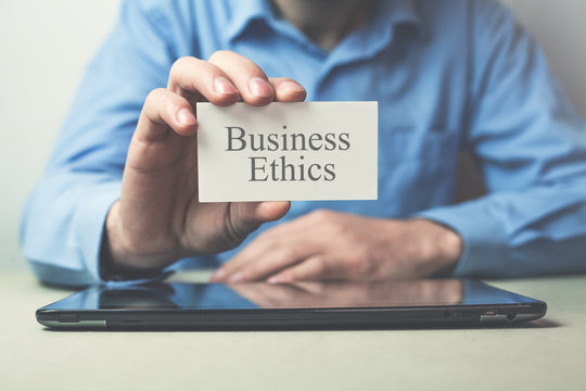 Businessman showing text Business Ethics on business card.