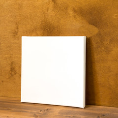 Blank square canvas on wooden background. Side view. Mock up poster for design. 