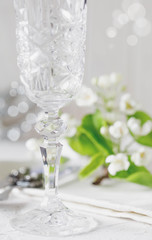 Wedding or Valentine's Day concept. Crystal champagne glass, branch with white  blossom and word love on background on white concrete table