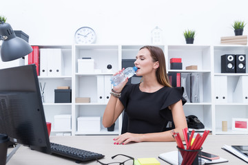 Beautiful girl drinking water from a bottle in the office