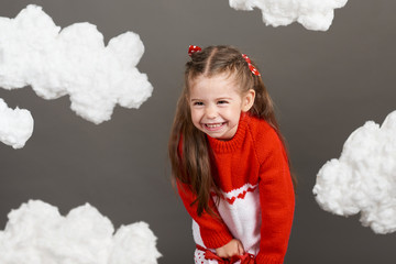 girl playing with clouds, dressed in red sweater, shot in the studio on a gray background