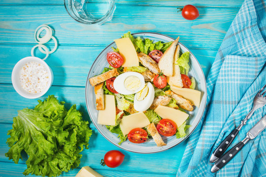 Fresh caesar salad in plate on blue wooden table.