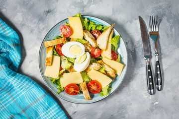 Fresh caesar salad in plate on concrete table.