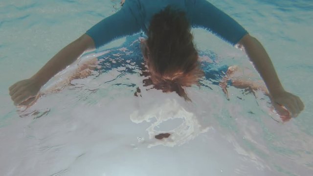 A Young Woman Relaxes Floating On The Turquoise Water Surface While She Is Filmed From Below, Producing A Strange Mirrored Image.