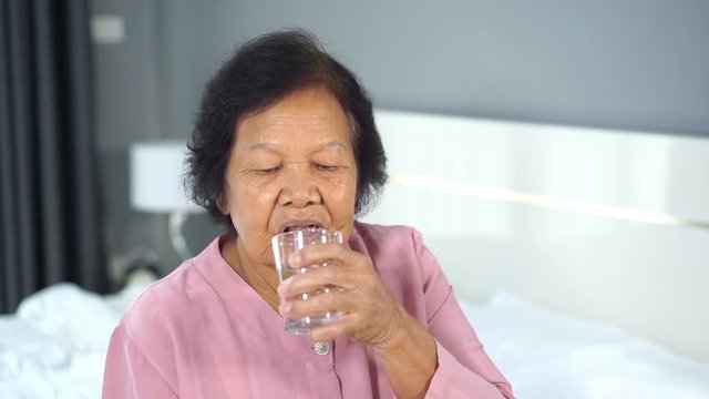 slow motion of senior woman drinking water in the bedroom