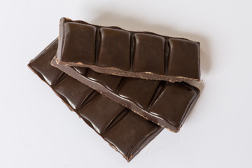 Dark chocolate pieces closeup on the white background.