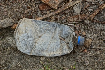 dirty plastic bottle lies on the ground