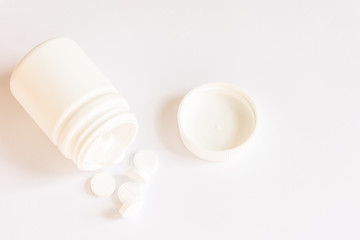 White pills in a bottle on white background.Copy space.Mockup for design.