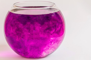 Abstract violet smoke wave in the water in a glass vase.