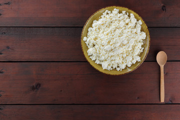 Cottage cheese on wooden boards, soft cheese on a yellow plate. Dairy product on a brown wooden background, healthy lifestyle. Copy space
