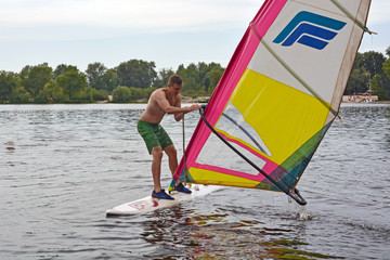 man stands on the Board in the water windsurfing