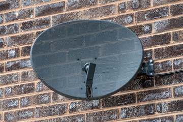 TV satellite dish mounted on a brick wall