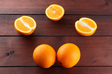 Fruits of oranges on a dark brown wooden background, halves of oranges on wooden boards. Copy space. Orange fruits for vegans. Citrus for breakfast