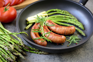 Sausages with herbs frying in a pan