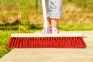 Woman using broom to clean up backyard patio
