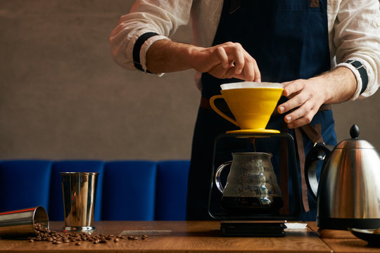 Professional Barista Or Coffee Barman Prepares Coffee By An Alternative Method Of Brewing, Pour Over, By Hot Water Spilling Through A Special Filter With Ground Powder