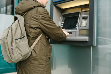 The tourist withdraws money from the ATM for further travel. Grabs a card from the ATM. Finance, credit card, withdrawal of money.