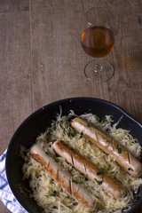 Salchichas en una sartén con una copa de vino Bratwurst