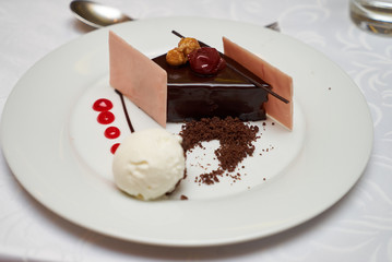 Black forest slice cake with cherry, vanilla ice-cream, chocolate dirt on a white plate, close-up. Tradidional delicious sweet dessert food 