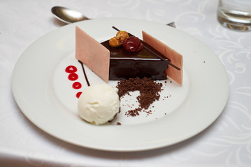Black forest slice cake with cherry, vanilla ice-cream, chocolate dirt on a white plate, close-up. Tradidional delicious sweet dessert food 