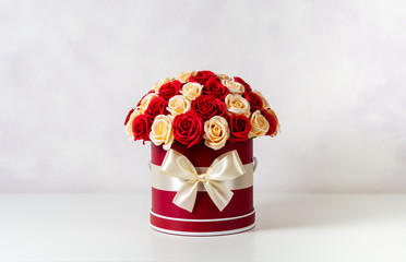 A bouquet of pink and white roses decorated in a hat box on a light background.