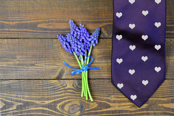 Fathers Day tie and grape hyacinth flowers on wooden background