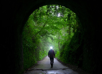 Hiker illuminating the path when entering a tunnel.