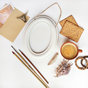 Minimalist composition made of white frame, artist's supplies, brushes, cup of coffee and decoration