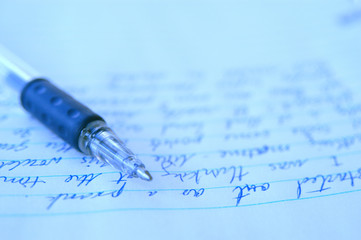 Still life of pen and paper. Blue ball point pen laying on the start of a creative writing home homework assignment.  Writing in blue ink on a sheet of college ruled notebook paper.