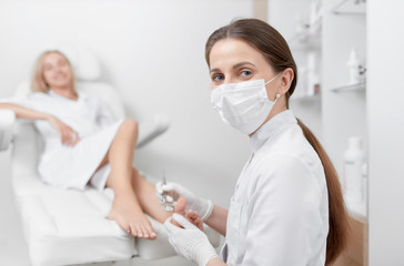 Podiatrist in mask on face looking at camera and working.