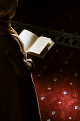 Muslim woman under the sunlight reading quran in a mosque