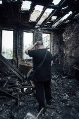 Sad man in burnt house. Loss and despair concept 