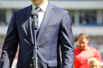 a man in a suit stands in front of a microphone