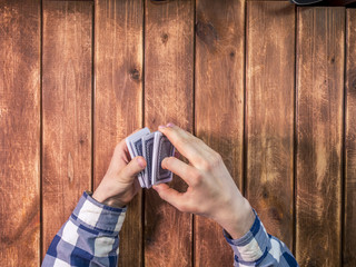 Fototapeta premium person hands manipulating with playing cards on a wooden background