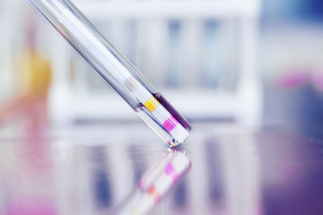 Test tube with an indicator strip on a light blurry background.