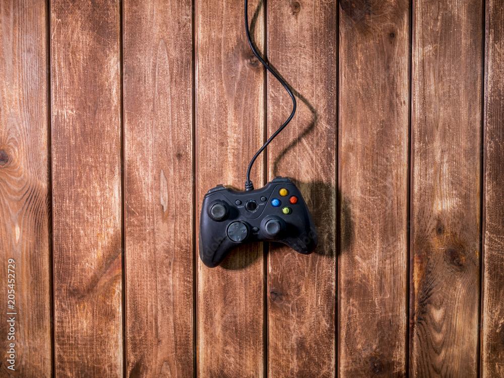 Wall mural one black modern video game gamepad on the wooden background