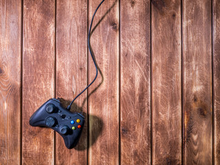 one black modern video game gamepad on the wooden background